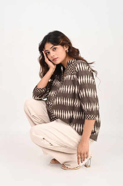 Woman wearing a patterned top and beige pants on a white background